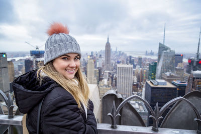 Portrait of smiling young woman in city during winter