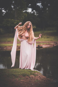 Young woman standing against lake