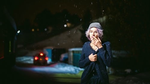 Close-up of young woman smoking cigarette at night