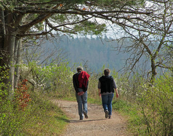 Rear view of man and woman walking on dirt road