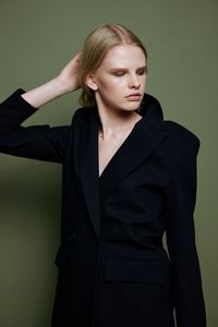 Portrait of young woman standing against black background