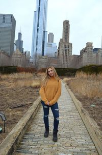 Full length portrait of young woman standing on railroad track