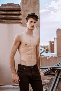 Portrait of shirtless man standing against sky