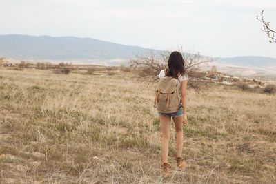 Rear view of young woman standing on field