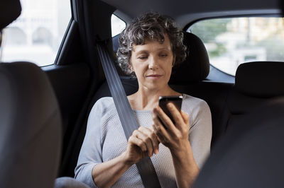 Mature woman using phone while travelling in car