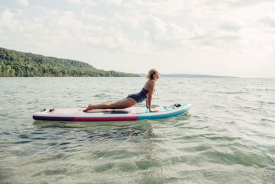 Woman on paddleboard in sea against sky