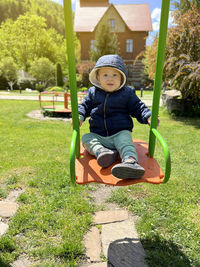 Portrait of boy sitting on swing at park