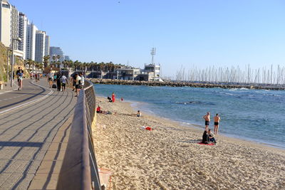 People on beach against clear sky