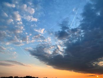 Low angle view of vapor trails in sky during sunset