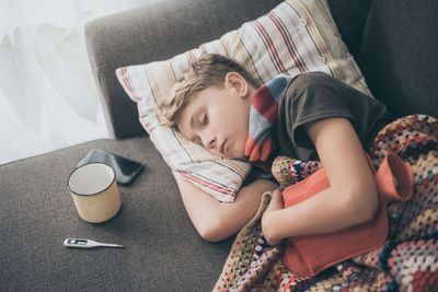 Ill boy sleeping on sofa at home