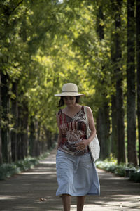 Full length of woman wearing hat standing against trees
