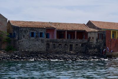 Houses by sea against sky in city