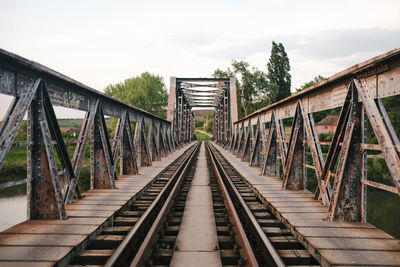 Footbridge over railroad tracks against sky