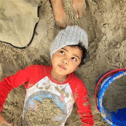 High angle view of cute boy lying on sand at beach