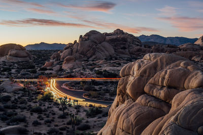 Light trails on street amidst rock formations 