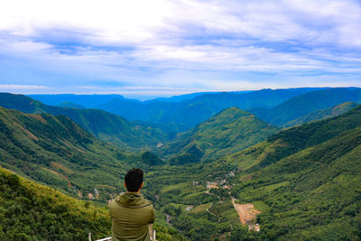 Rear view of man looking at mountains against sky