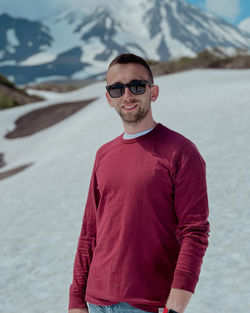 Portrait of young man standing against mountain