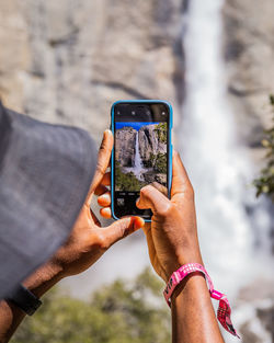 Midsection of man photographing with mobile phone