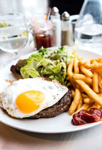 Close-up of fried egg with french fries and meat served on table