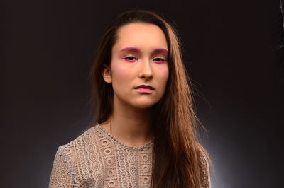 Close-up portrait of young woman against black background