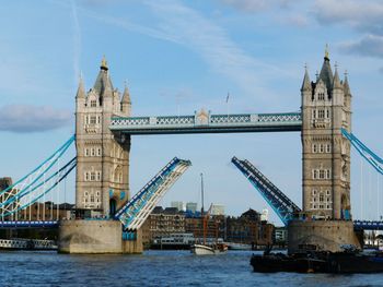 Tower bridge over river against sky in city