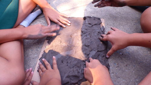 High angle view of people hands on sand