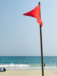 Red flag at beach against clear sky