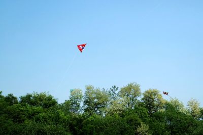 Low angle view of kite flying against clear blue sky