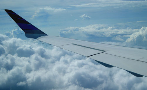 Cropped image of airplane flying over cloudy sky