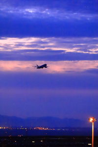 Low angle view of airplane flying against sky at sunset