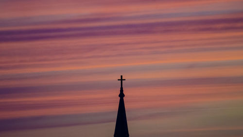 Silhouette high section of church against cloudy sky