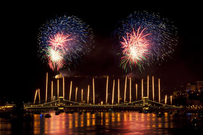 Illuminated chain bridge over danube river with firework display at night