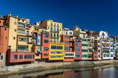 Buildings by river against clear sky