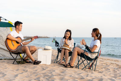 Rear view of friends sitting at beach