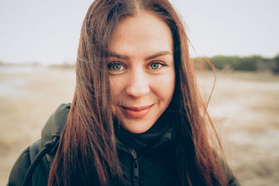 Portrait of young smiling brunette woman in winter jacket looking at camera. person