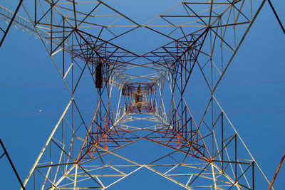 Low angle view of electricity pylon against clear blue sky