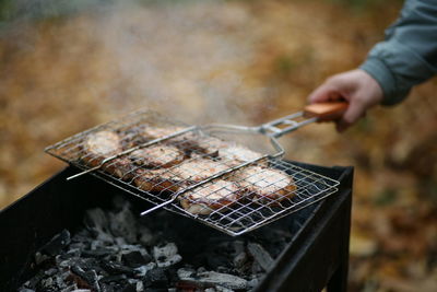 Cropped hand of man preparing food on barbecue grill