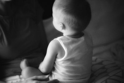 Cute baby boy sitting on bed at home