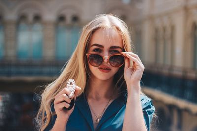 Portrait of beautiful woman wearing sunglasses against building