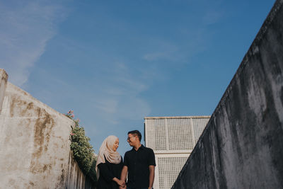 People standing on wall against sky