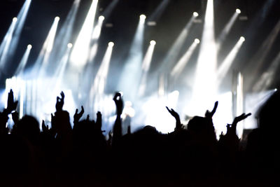 Rear view of silhouette of crowd with arms outstretched at concert. summer music festival concept