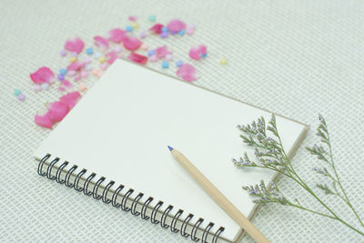 High angle view of pencil with blank book on table