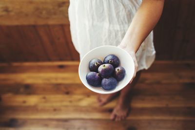 High angle view of woman holding ice cream in bowl on table