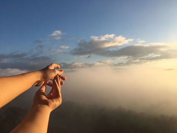 Cropped image of man and woman gesturing against sky 