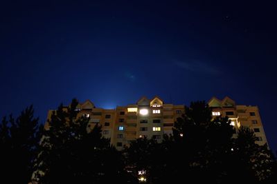 Illuminated city against blue sky at night