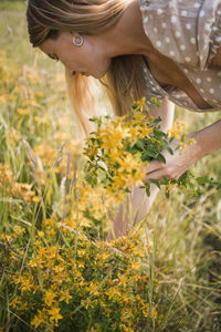 Woman standing by flowering plants on field