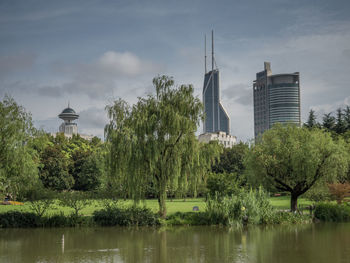 Trees and buildings against cloudy sky