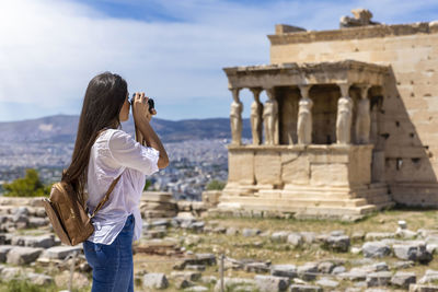 Side view of woman photographing old building