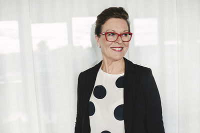 Confident smiling businesswoman standing at office