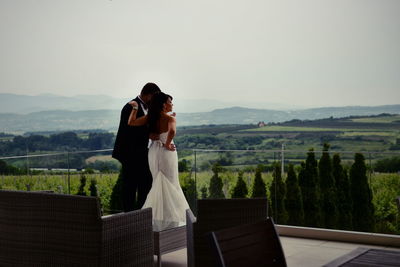 Couple standing on mountain against sky